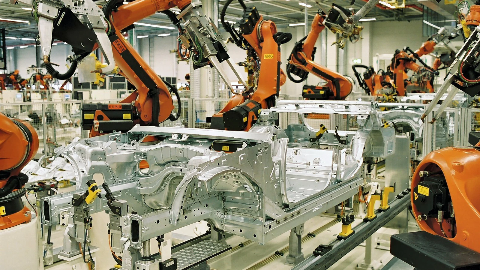 BMW 라이프치히 생산라인에서 차체를 둘러싸고 용접하는 주황색 KUKA 산업용 로봇